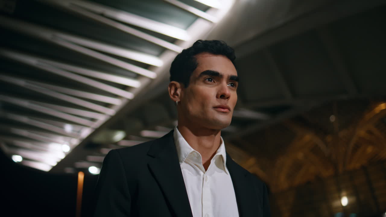 Serious manager crossing night airport terminal closeup. Man walking dark place