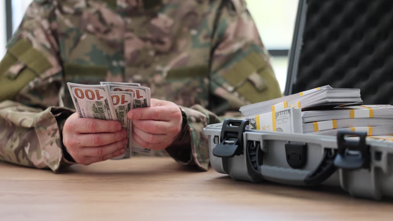 Military personnel counting money from a suitcase
