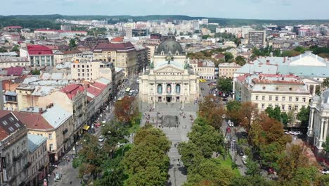 Antena-Del-Teatro-Académico-Nacional-De-ópera-Y-Ballet-De-Lviv-En-Lviv-Ucrania-Durante-Un-Día-De-Verano-Con-Autos-Conduciendo,-Gente-Caminando-En-La-Plaza-Y-Edificios-Europeos-En-El-Fondo