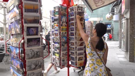 Female-Asian-tourist-picking-postcards-at-souvenir-store-in-Vienna,-Austria