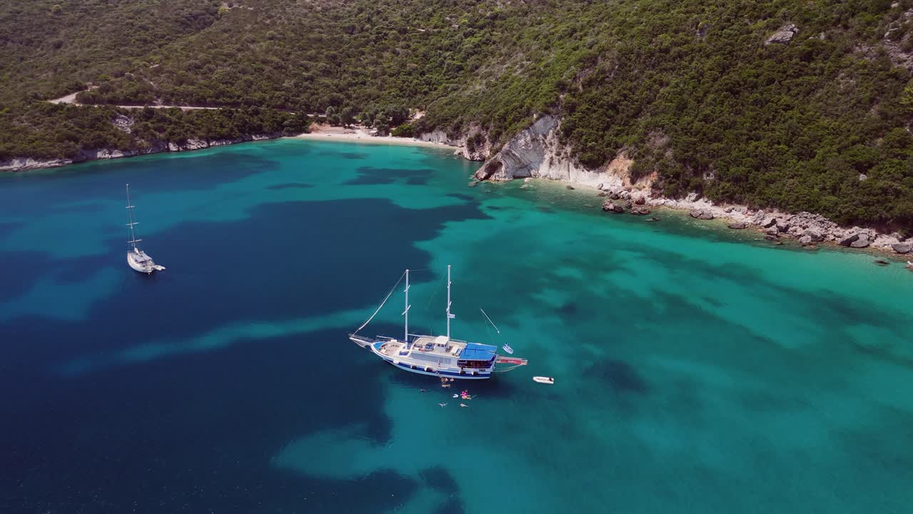 Aerial circles tourists swimming in clear warm water by tour boat