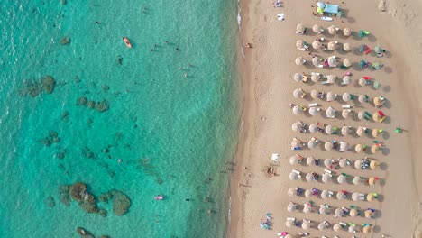 Von-Oben-Nach-Unten-Geschossenes-Unberührtes-Türkisfarbenes-Wasser-Mit-Untergetauchten-Felsen-Und-Sonnenschirmen,-Strand-Von-Falassarna