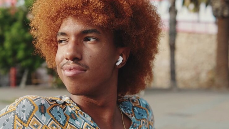 Young Man with Afro Hair Listening to Music Outdoors