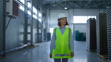 Female-storage-employee-walking-in-factory-storehouse-checking-distribution