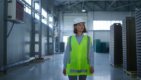 empleada de almacén caminando en el almacén de la fábrica comprobando la distribución