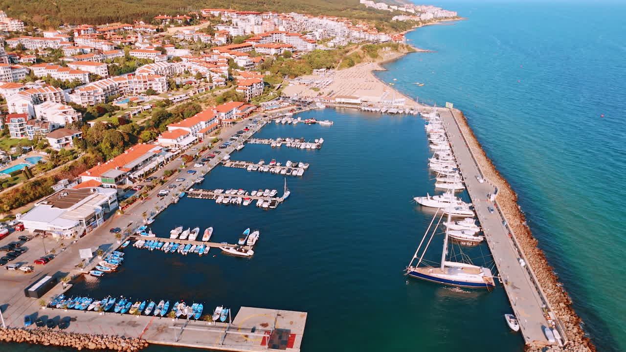 Coastal marina with boats in clear water. View of a vibrant marina filled with boats under a bright sky, adjacent to a scenic beach on a summer day