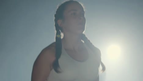 young caucasian sportswoman with braided pigtails jumping rope in boxing ring