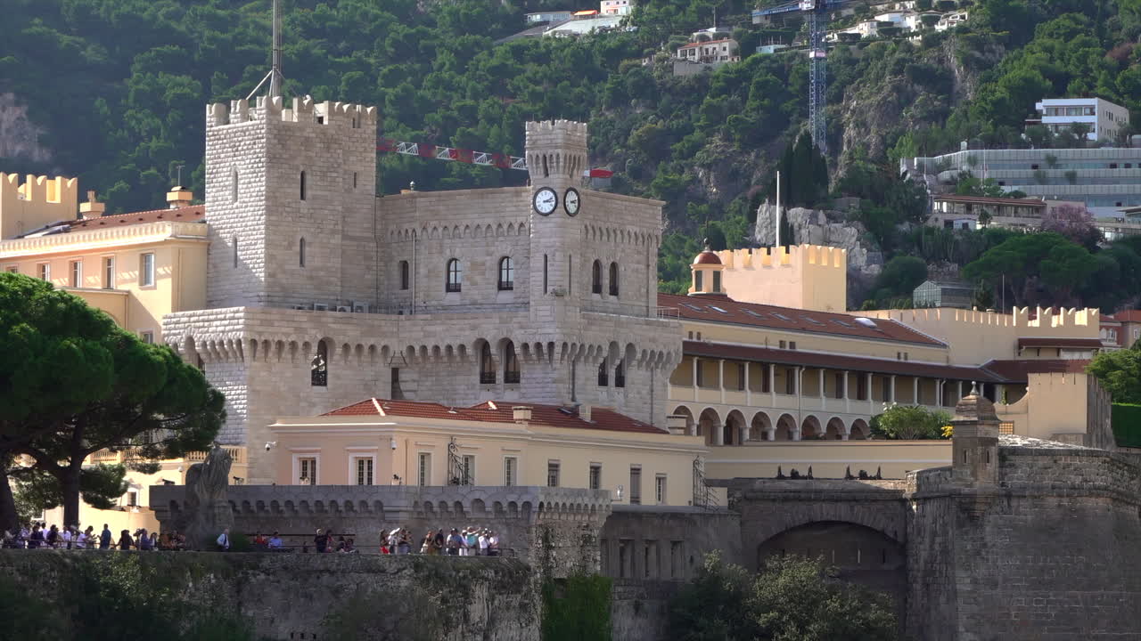 Distant view of the Prince's Palace of Monaco and medieval ramparts perched above Monaco, with visitors walking around