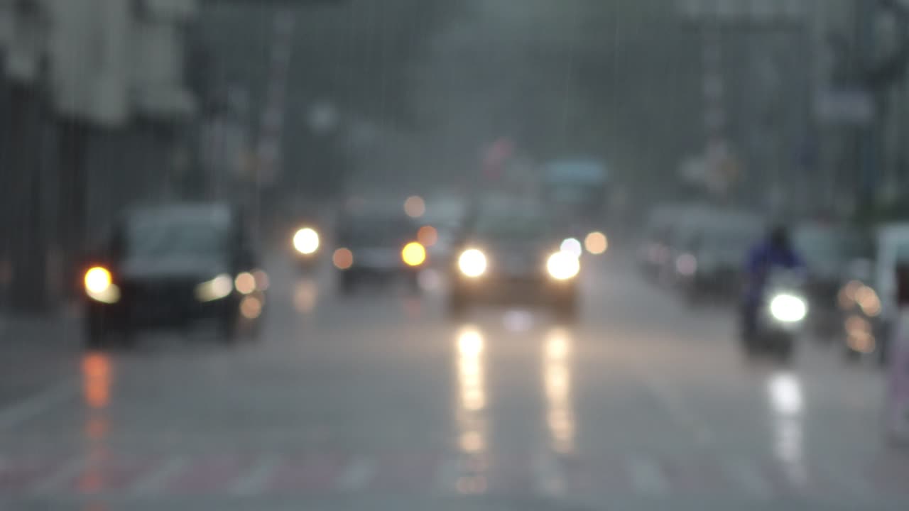 Blurry footage of highway with vehicle headlights during heavy rain condition