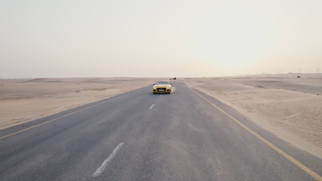 coche amarillo conduciendo en una carretera del desierto