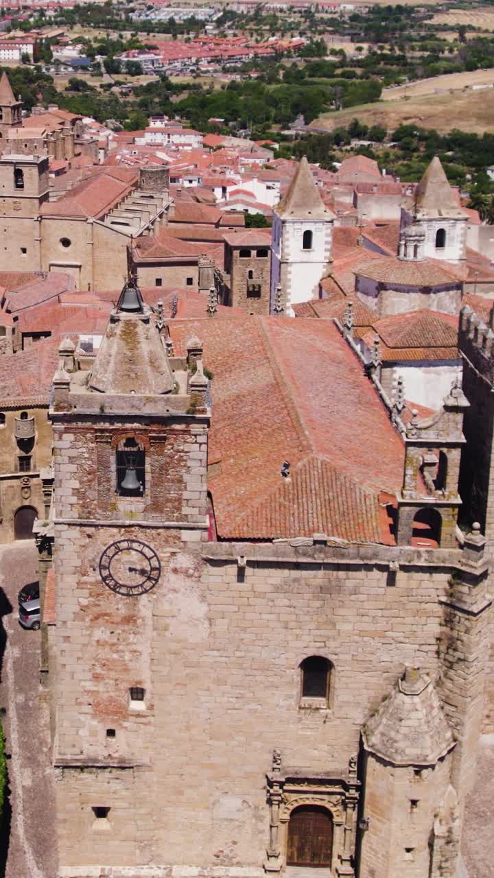 Vista aérea vertical orbitando las iglesias católicas de San Francisco Javier y San Mateo, mostrando los coloridos tejados de terracota de Cáceres, España