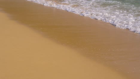 ocean waves rolling into golden sandy beach in slow motion