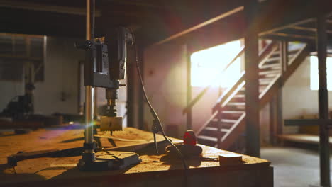 camera is panning across sunlit dusty workbench as drill press is entering frame for feature reveal