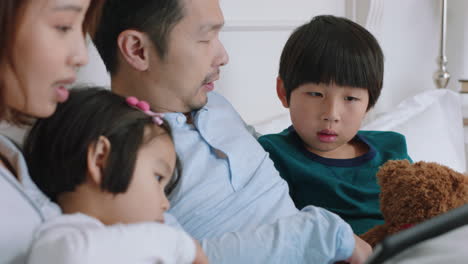 집에서 태블릿 컴퓨터를 사용하는 행복한 아시아 가족 어머니와 아버지는 자녀들과 함께 엔터테인먼트를보고 터치 스크린 장치에서 게임을하고 배우고 즐겁게 침대에서 휴식을 취합니다 4k 영상