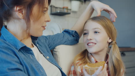 close up of the cute blonde teen girl talking with her pretty mother and holding a bread with peanut butter. indoor