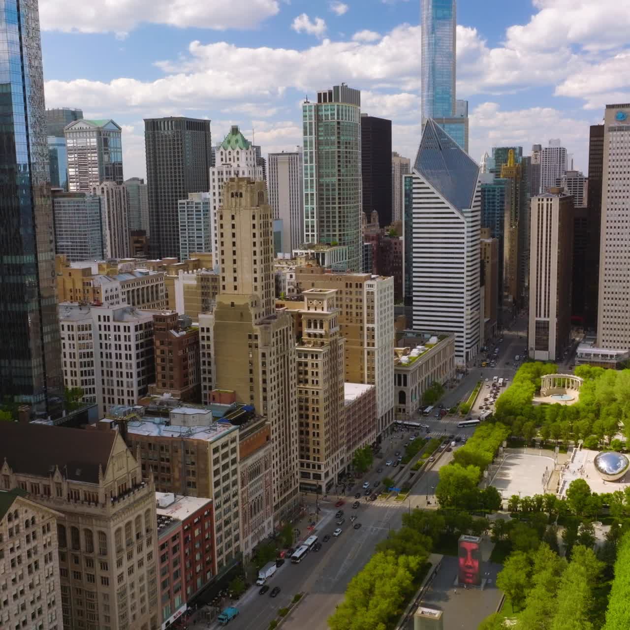Green beautiful Millennium Park surrounded by amazing Chicago architecture. Multi-lane road separating park from buildings