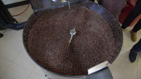 coffee roasting machine drum with roasted coffee beans pouring into it after roasting