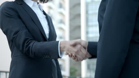 confident employees meeting on street and shaking hands