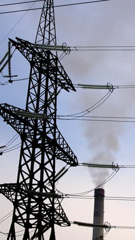 electricity pylons and smoke from pipes. wires of high-voltage transmission lines and pipes of industrial plant with thick smoke. vertical video