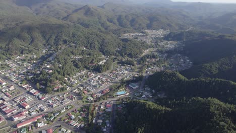 Vista-Aérea-De-La-Histórica-Ciudad-Minera-De-Queenstown-Que-Revela-La-Cordillera-De-La-Costa-Oeste-En-Tasmania,-Australia