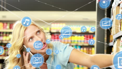 animación de iconos conectados sobre mujer caucásica hablando por teléfono móvil en la tienda de comestibles