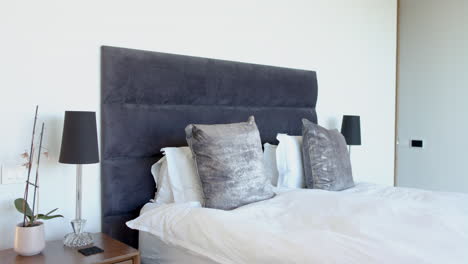 a modern bedroom features a large grey headboard and matching lamps with copy space