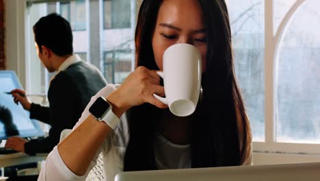 Ejecutiva-Femenina-Usando-Una-Computadora-Portátil-Mientras-Toma-Un-Café