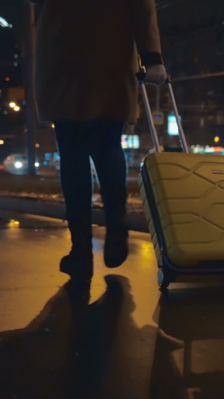 Una persona caminando con una maleta por la ciudad de noche