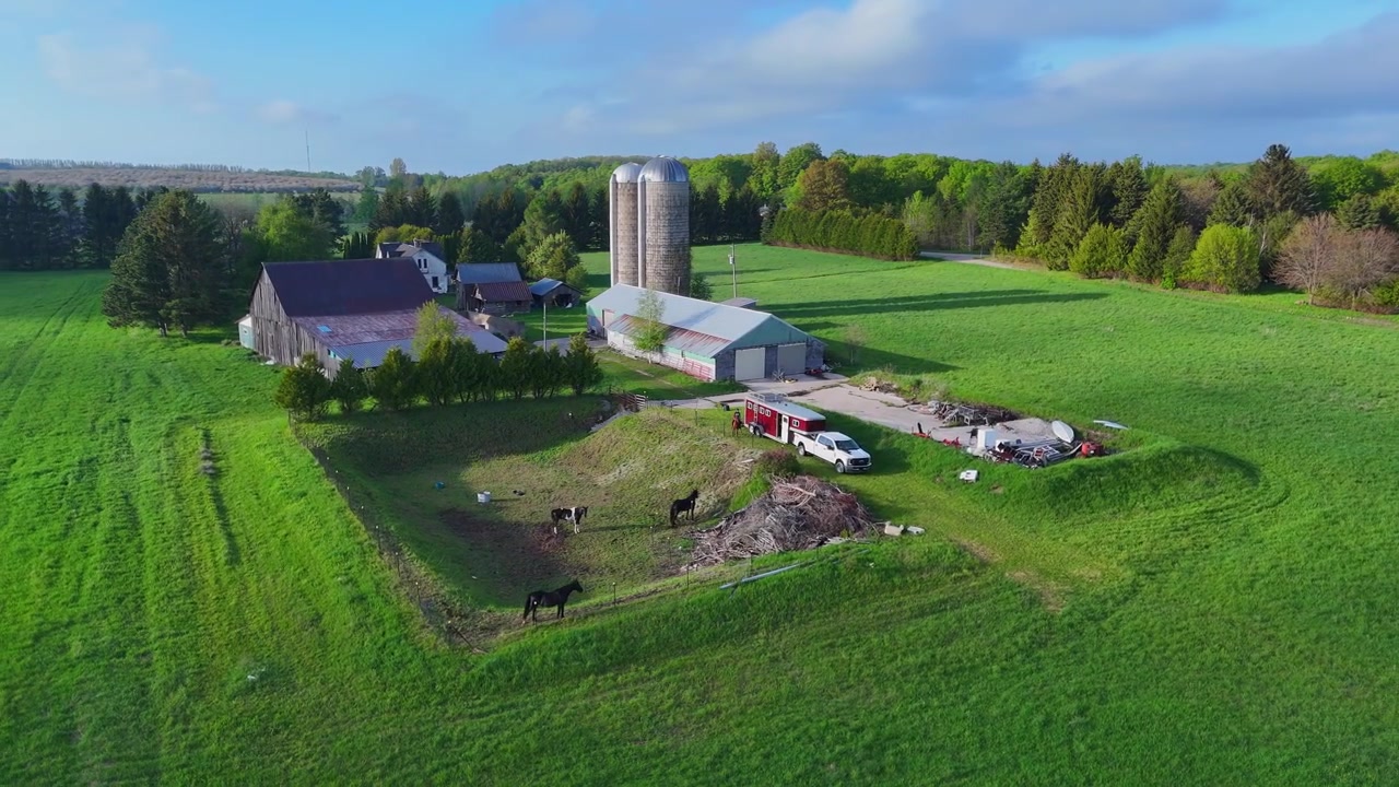 Landbrug med heste, lade og silo under en forbipasserende skyggesky i Leelanau County, Michigan, USA