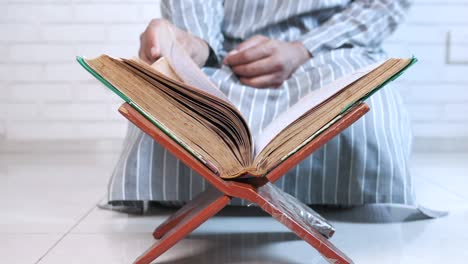 muslim man sitting floor reading holy book quran