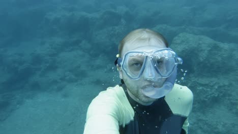 a man underwater with goggles and breathing apparatus slowly getting above the beach surface in paralia emplisi, beach