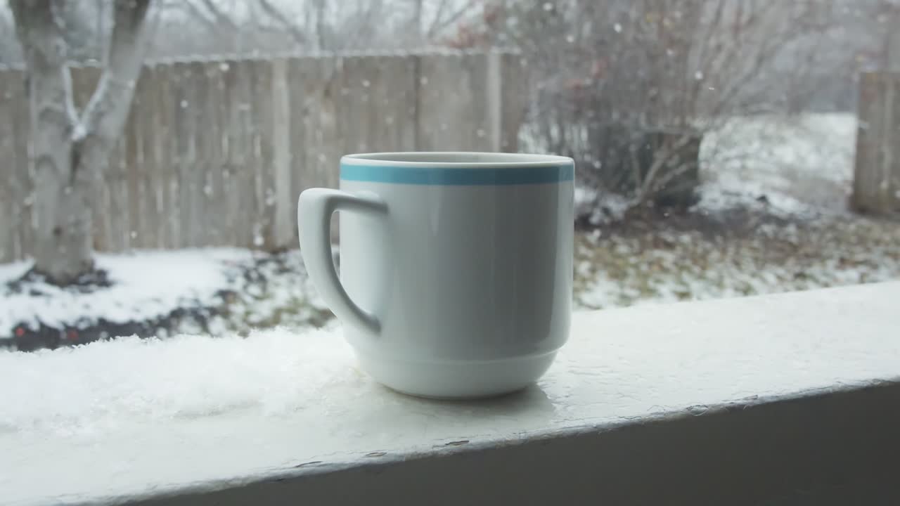 movimiento lento de una taza de bebida caliente con una caída de nieve de invierno en el fondo al aire libre