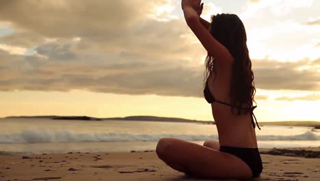 una morena pacífica meditando en la arena al atardecer