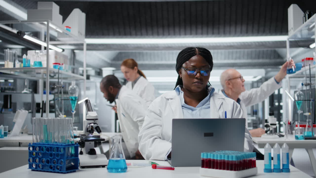 Smiling cytotechnologist works on laptop in lab, studying genomics