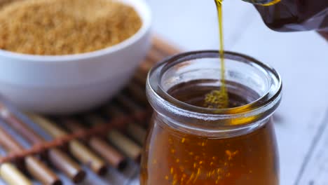 pouring oil into small glass bottle with brown sugar in background