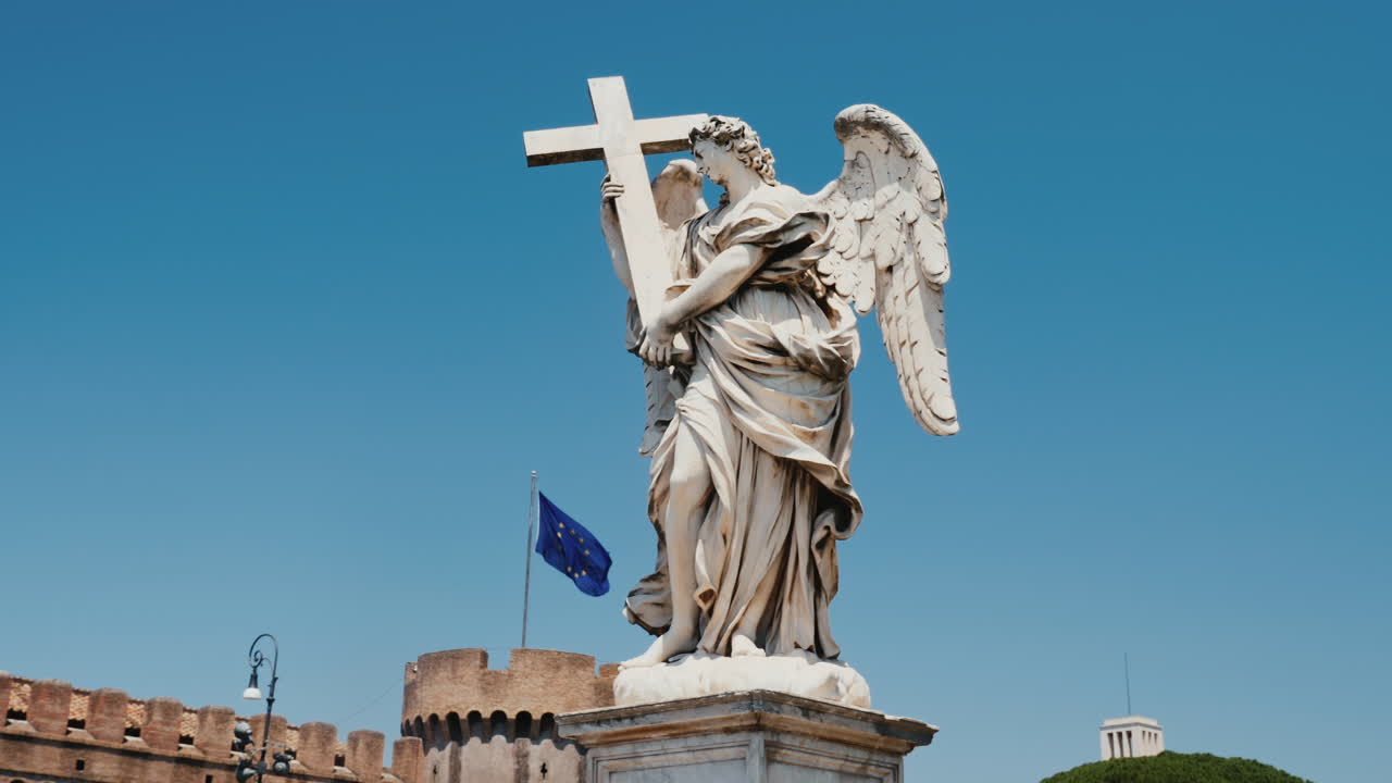 tiro de steadicam: estatua de un ángel con una cruz en el fondo castel santangelo y bandera de la unión europea