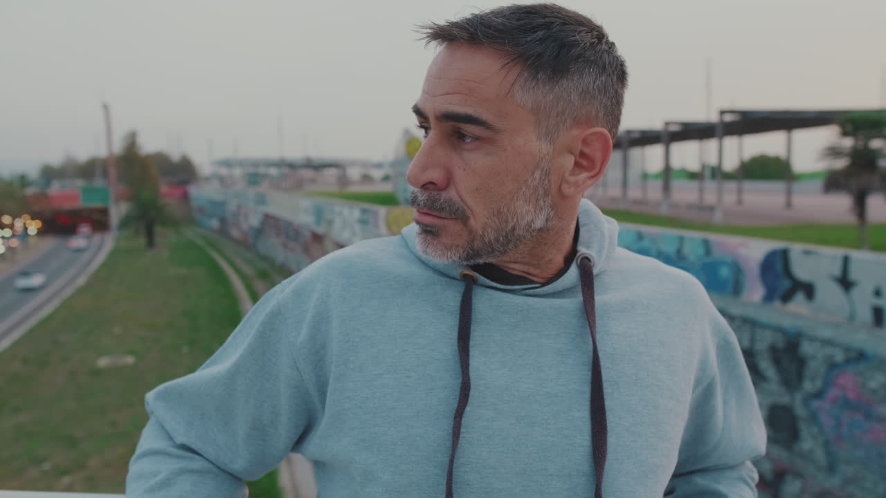 Man in hoodie on urban bridge