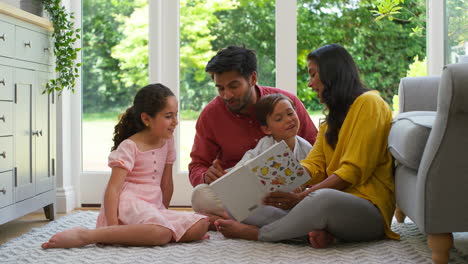 smiling family at home sitting on floor in lounge reading book together