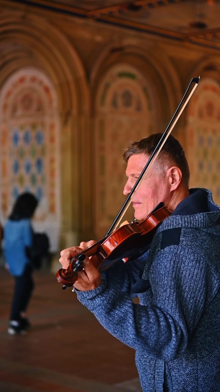 Nova Iorque, EUA, 21 de junho de 2026: Violinista tocando música no Central Park, Nova Iorque. Close-up de perfil de um músico de rua masculino segurando um violino dentro da arcada do Bethesda Terrace