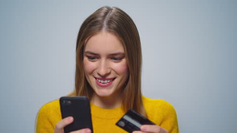 Mujer-Atractiva-Enfocada-Comprando-Con-éxito-En-Línea-En-Un-Teléfono-Inteligente-En-El-Estudio.