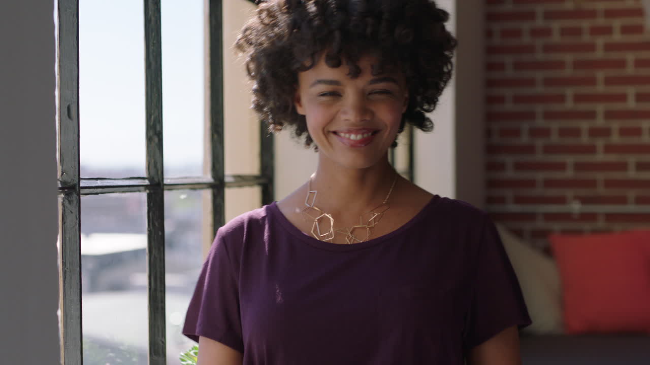 portrait successful african american woman looking out window smiling at camera enjoying positive lifestyle planning ahead relaxing at home black female with trendy afro hairstyle