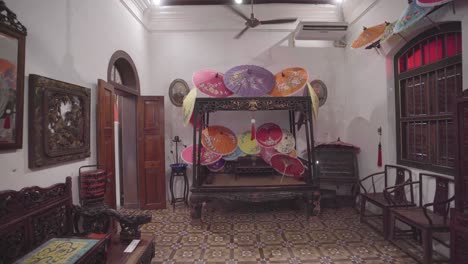 several asian handmade umbrellas on peranakan bed frame, dolly out, close up
