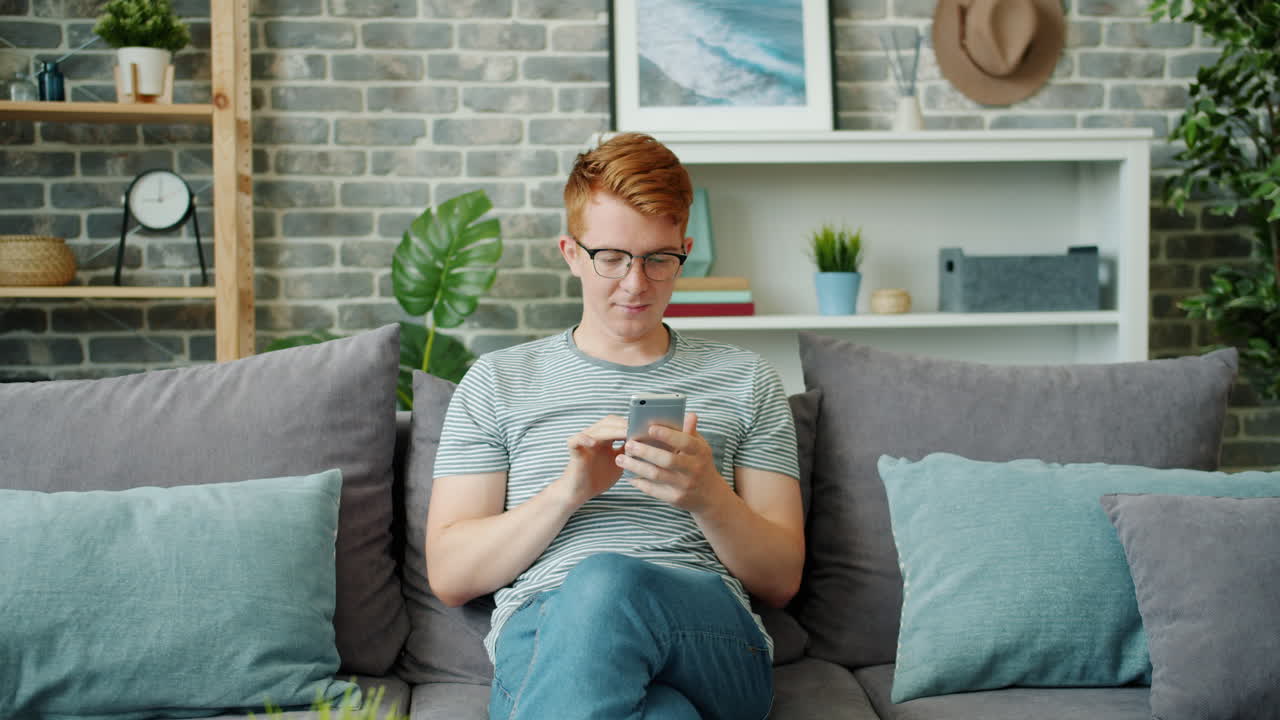 소파에서 스마트폰을 사용하는 젊은 남자