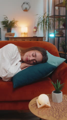 tired young caucasian woman girl enjoying sleeping relaxing rest on sofa in living room apartment