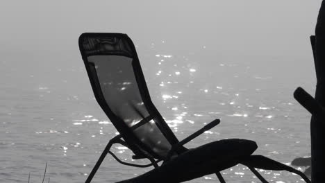 silhouette of sun lounger in front of hazy sea, slow motion