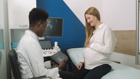 doctor showing ultrasound scan to pregnant woman