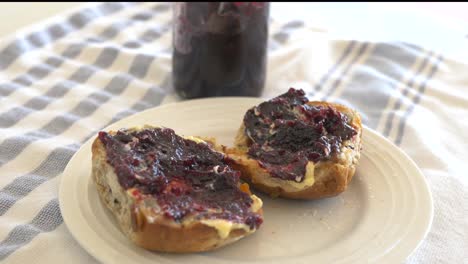 Sartén-A-Cámara-Lenta-Alrededor-De-Bollos-Cruzados-Calientes-Con-Mermelada-Y-Mantequilla-Sentados-En-Un-Plato-En-Pascua