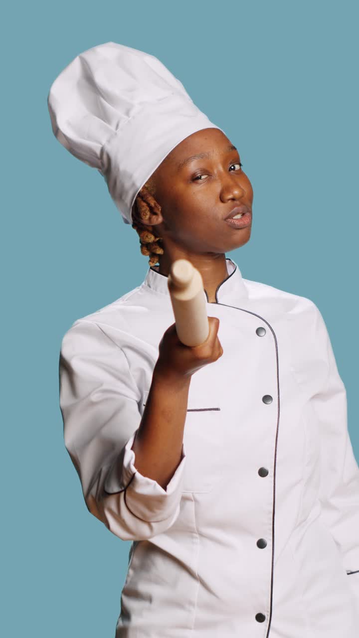 Video verticale: chef afroamericano che indica la telecamera con un matterello di legno