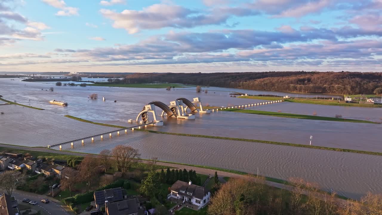 Drone shot flying towards the weir and door of the weir open during high waterlevels with Ships passing thru