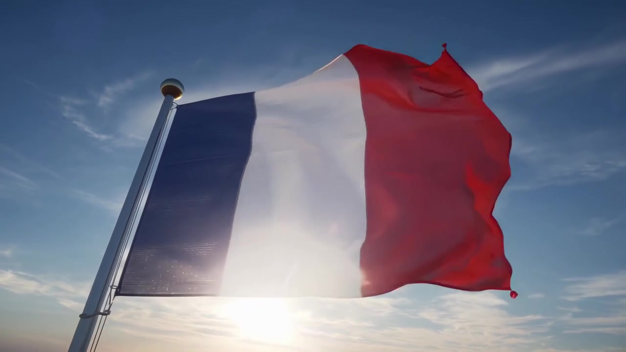 Bandiera francese che sventola alla luce del sole con bagliore dell'obiettivo contro un cielo blu